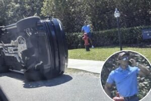 Tiger Woods standing next to overturned black Land Rover SUV after rollover crash on Jupiter Island Florida on March 27 2026 before DUI arrest