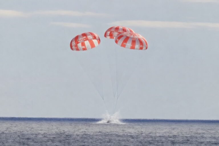 NASA Artemis II Orion spacecraft Integrity with four astronauts descending on parachutes toward Pacific Ocean off San Diego during splashdown April 10 2026