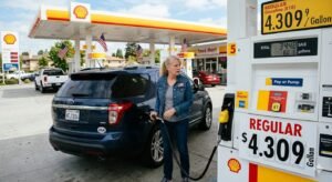 American driver at gas station pump with price display showing $4.30 per gallon as Brent crude oil surges to $126 barrel during Iran war May 1 2026