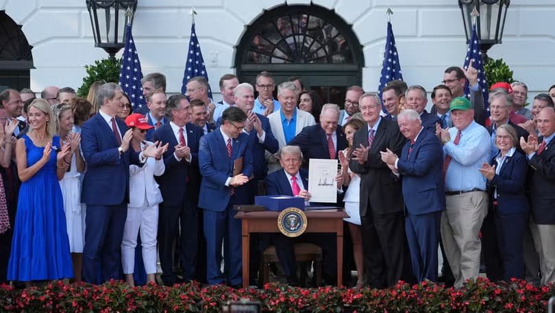 President Trump signing One Big Beautiful Bill Act on July 4 2025 surrounded by Republican lawmakers representing sweeping tax and spending legislation affecting millions of Americans in 2026